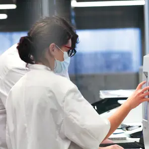 Een vrouw met een mondkapje werkt met een analyse machine in een laboratorium